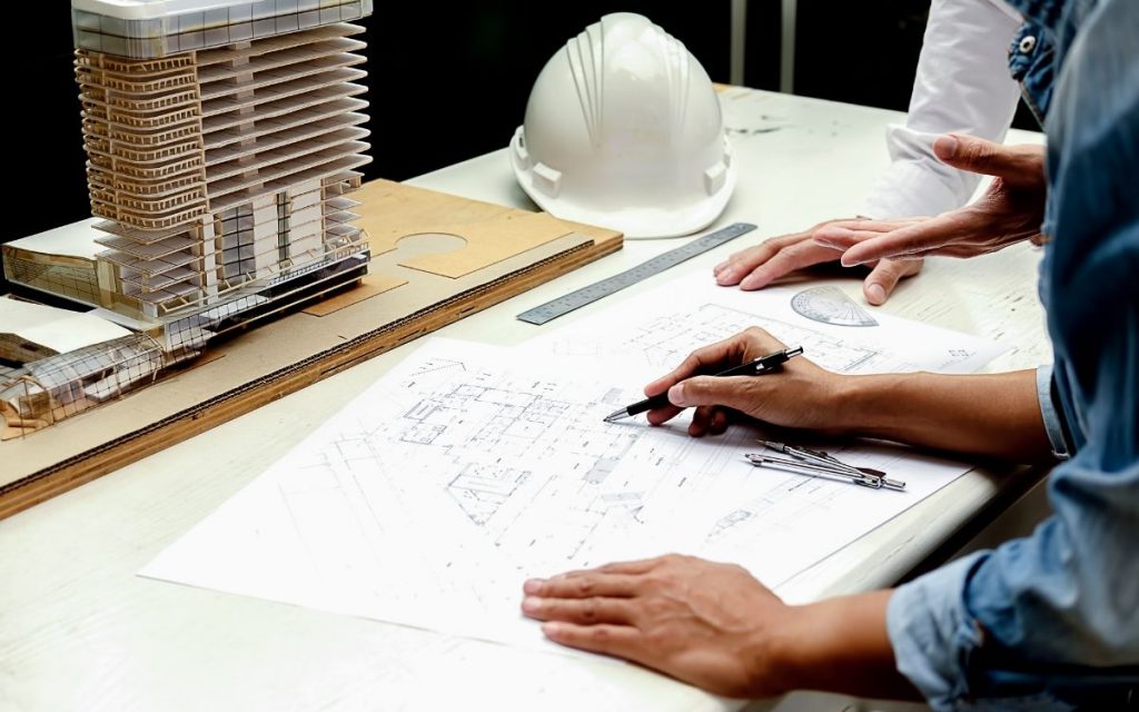 Two people reviewing construction plans laid out on a table